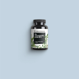 Eine Flasche Vitamin C mit grünen Blättern auf blauem Hintergrund, die natürliche Elemente zur Geltung bringt.